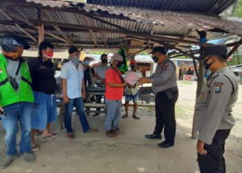 Kanit Binmas memberikan helm kepada pengemudi ojek di pangkalan pintu masuk pelabuhan Pengumpan Sekupang. (Foto: Muhamad Ishlahuddin)