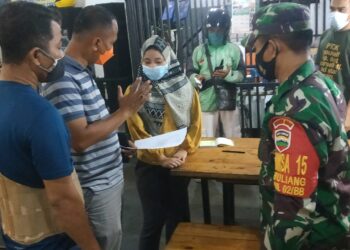 Petugas Covid-19 saat memberikan surat imbauan kepada pemilik rumah makan tempat Sari bekerja. (Foto: Meilina Zalfiregar)