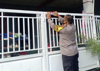 Petugas Babinkantibmas Polsek Batam Kota memasang stiker Isoman di salah satu rumah warga di Kelurahan Taman Baloi, Batam, Kepulauan Riau, Senin, 23 Agustus 2021. (Foto: Polsek Batam Kota)