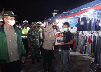 Polisi membagikan paket sembako kepada masyarakat sambil patroli PPKM Level 4 di Kota Batam, Kepulauan Riau. (Foto: Humas Polda)