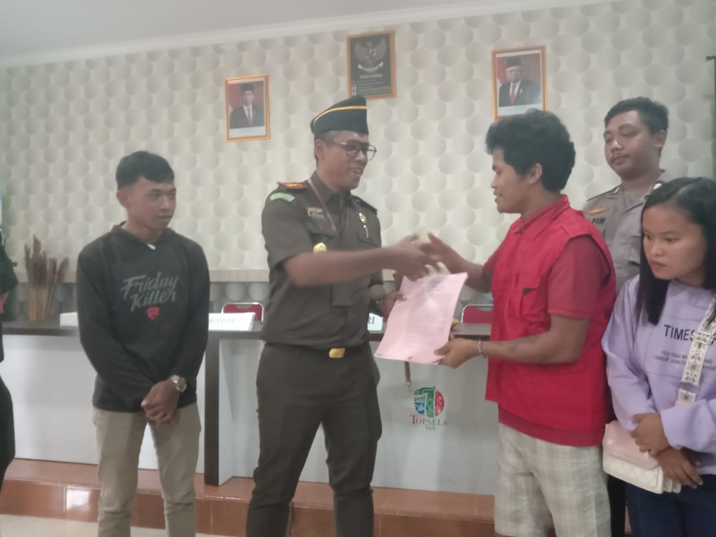Kepala Kejari Bintan I Wayan Eka Widdyara, menyalami Julianus (rompi merah) usai memberikan Restorative Justice (RJ) yang berlangsung di Balai Desa Toapaya Selatan, Kecamatan Toapaya, Kabupaten Bintan, Kamis (26/01/2023). (Foto: HMS/ Yulita Dani).