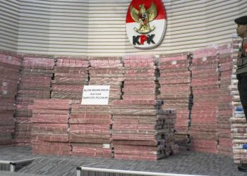 Polisi berjaga di depan tumpukan uang tunai Rp300 miliar saat jumpa pers kasus korupsi Taspen di gedung
Merah Putih Komisi Pemberantasan Korupsi (KPK), Jakarta, Kamis, 20 November 2025. (Foto: Ist / merdeka.com).